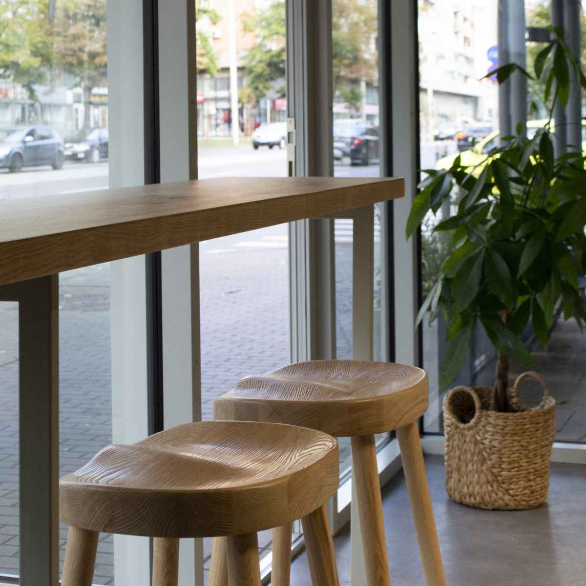 Două scaune cu șezut curbat și un blat de masă înalt așezat la fereastră