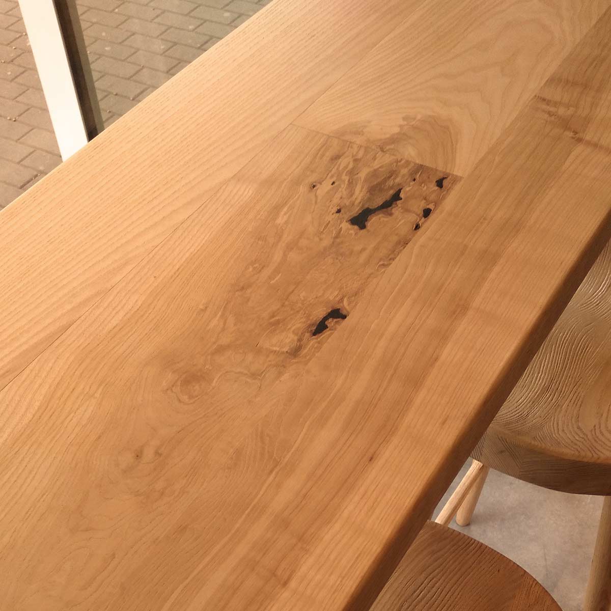 Detaliu cu noduri și fibre ondulate în blatul din lemn de frasin masiv