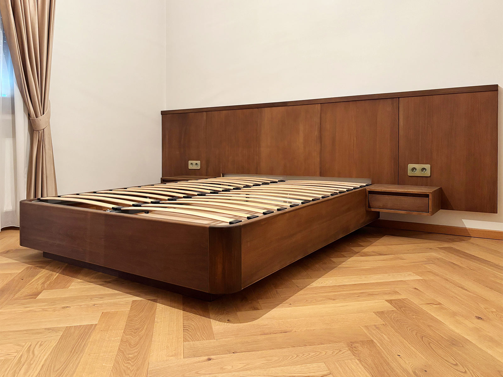 Dormitor cu pat din lemn masiv în nuanță cafeniu închis cu tăblie din panouri îmbinate și noptiere suspendate