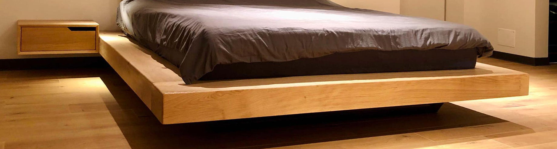 Detaliu cu cadru de pat din lemn intr-un dormitor cu iluminat de seara